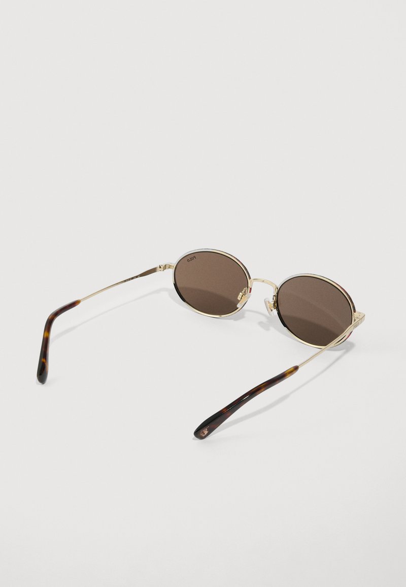 Round sunglasses with brown lenses, gold metal frame, and tortoiseshell-patterned arms. Lightweight design with subtle branding on lenses.