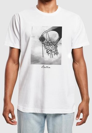 Mand iført hvid t-shirt med sort-hvidt foto af en basketballkurv og net samt ordet "Ballin" under billedet.