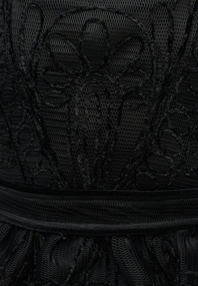 Μαύρο διάφανο ύφασμα με περίτεχνη κεντητή δαντέλα σε σχέδιο λουλουδιών και λεπτομέρεια στη ζώνη, παρουσιάζοντας υφή και διακοσμητικό μοτίβο στο ύφασμα.