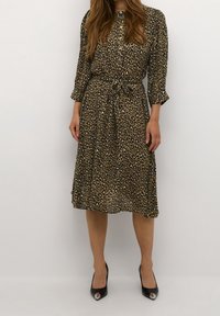 Midi šaty s leopardím potiskem, páskem, dlouhými rukávy, skládacím sukněm, vyrobené z lehké látky v zemitých tónech, doplněné černými podpatky.