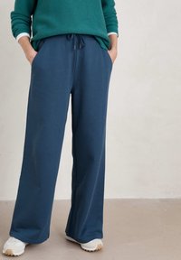 Blå vida byxor i mjukt tyg, med resårmidja och snörning, sidfickor och en avslappnad passform.