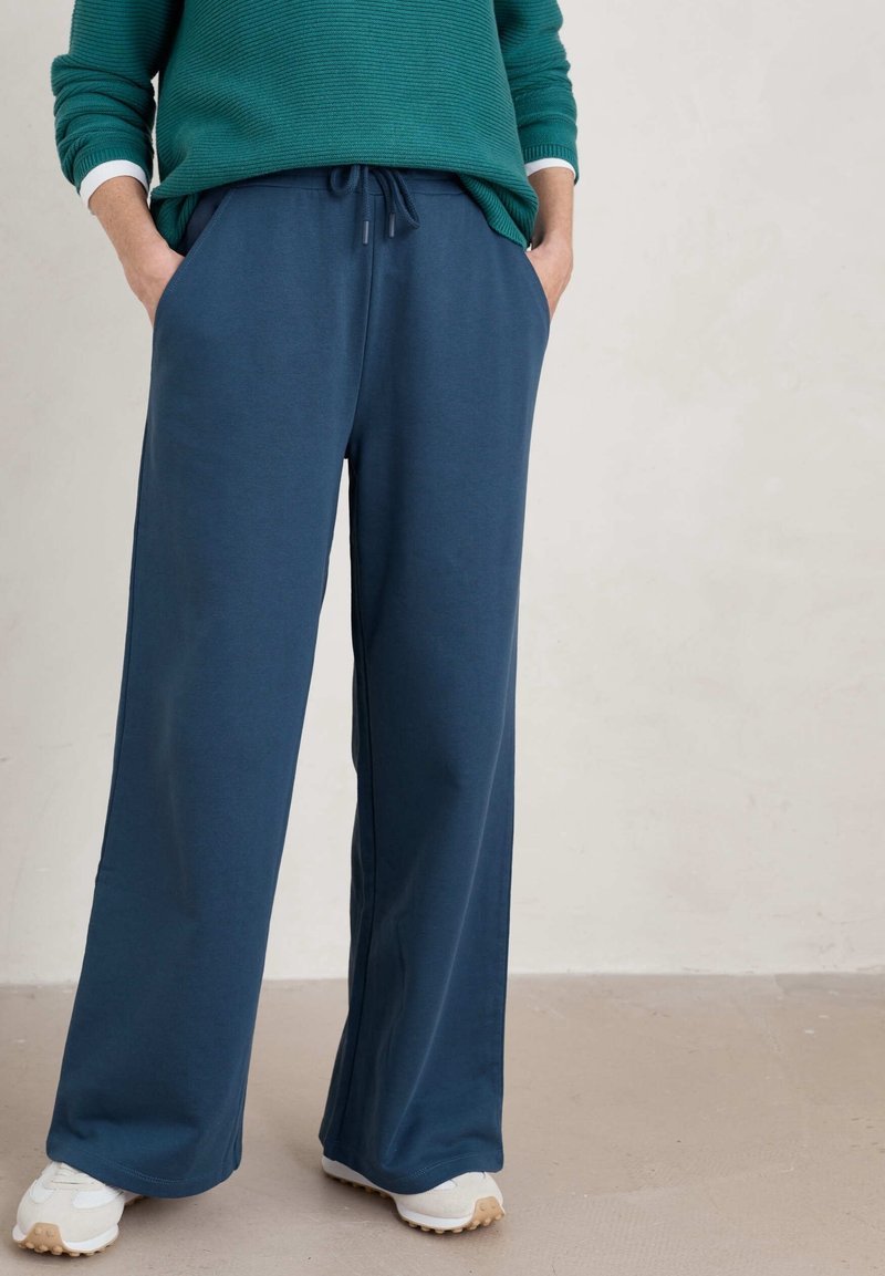 Blå vida byxor i mjukt tyg, med resårmidja och snörning, sidfickor och en avslappnad passform.