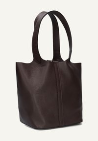 Donkerbruin, gestructureerde leren tote bag met twee lange handvaten en een verticale naad aan de voorkant, rechtop staand op een lichte achtergrond.