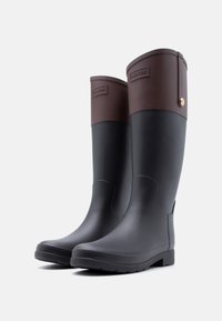 Ζευγάρι μαύρες και καφέ αδιάβροχες μπότες Hunter με λογότυπο στον άνω κορμό, τοποθετημένες δίπλα-δίπλα σε λευκό φόντο.
