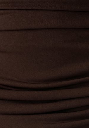 Smeđa tkanina s mekom teksturom, koja sadrži suptilne nabore i glatku završnu obradu. Materijal izgleda rastezljivo i prilagođava se obliku tijela.