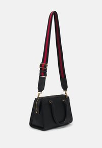 Borsa nera con due manici, chiusura con zip e tracolla staccabile con strisce rosse e navy. Accentuata con accessori in metallo color oro.