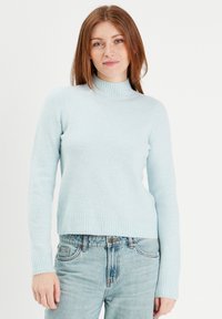 Lyseblå turtleneck sweater lavet af et blødt, struktureret stof med ribbede manchetter og kant. Kombineret med lyseblå denimjeans.
