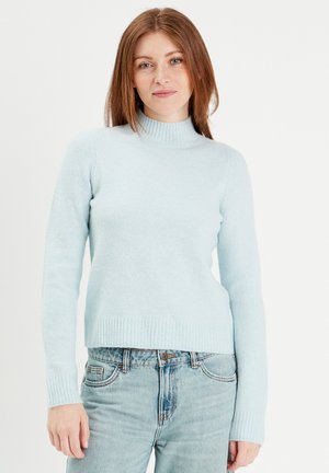 Lichtblauwe coltrui gemaakt van een zachte, textuurstof met geribbelde boorden en zoom. Gecombineerd met lichtblauwe denim jeans.