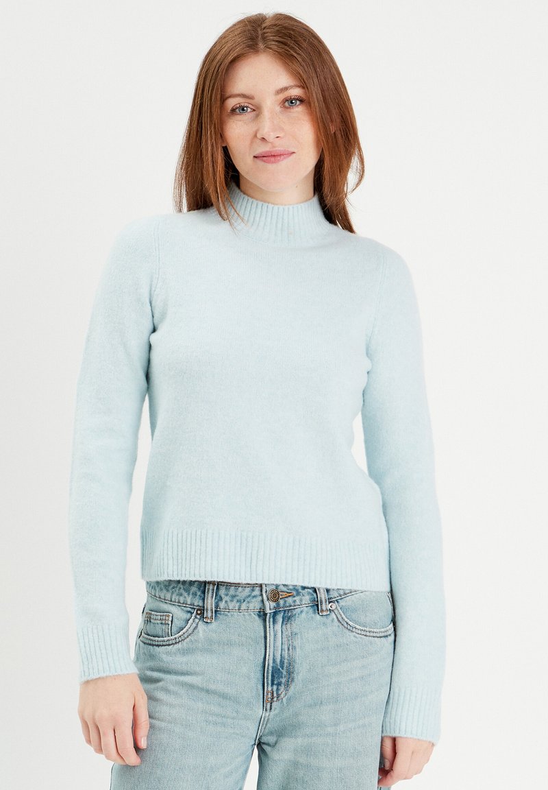 Lyseblå turtleneck sweater lavet af et blødt, struktureret stof med ribbede manchetter og kant. Kombineret med lyseblå denimjeans.