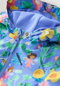 Jasně modrá pláštěnka s květinovým a hmyzím vzorem. Měkká levandulová fleecová podšívka, kapuce se stahovací šňůrkou a zapínání na zip.