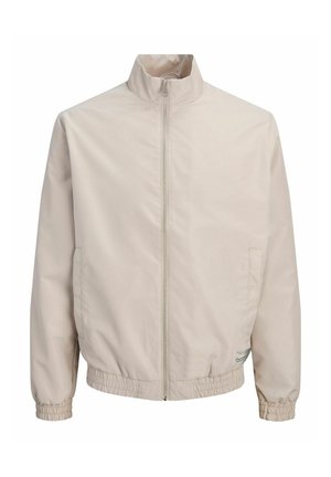 Beige lynlåsjakke med ståkrave, elastiske manchetter og talje samt sidelommer, vist på hvid baggrund.