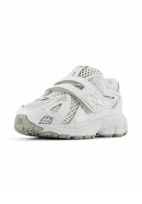 Chaussure de sport blanche avec un dessus en maille, bande Velcro, semelle texturée et accents gris. Comprend un logo latéral et un design ventilé.