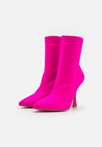 Lys pink, strækstof ankelstøvler med spidse tæer og slanke høje hæle, der har synlige sømme og en glat tekstur.