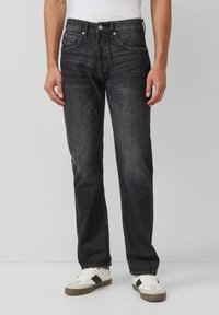 Dunkelgraue Jeans mit geradem Bein, fünf Taschen, Metallknopfverschluss und leichter Wischtechnik. Getragen mit weißen Turnschuhen.