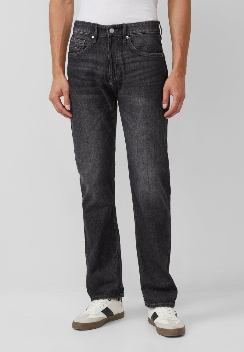 Dunkelgraue Jeans mit geradem Bein, fünf Taschen, Metallknopfverschluss und leichter Wischtechnik. Getragen mit weißen Turnschuhen.