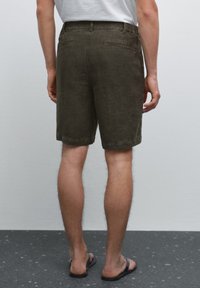 Olive green shorts made of soft fabric, featuring a relaxed fit, two back pockets, and a hem that falls just above the knee.