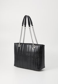 Zwarte leren totebag met verticale stiksels, zilveren kettinghandvaten en een gladde textuur. Vierkante vorm, ruime binnenkant en zilveren hardware.