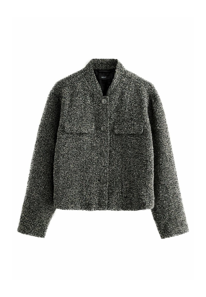 Hallhalline tweed jakk, lühenen lõikega, kahe eesmise taskuga, ümarate kraega ja nööbiga kinnitustega. Tekstuuriga kangas, millel on kalasabamuster.