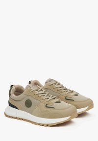 Beżowe sneakersy z siateczkowymi i zamszowymi akcentami, z białą środkową podeszwą, gumową podeszwą zewnętrzną i okrągłym logo po bocznej stronie.