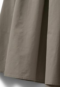 Falda de tela lisa color marrón claro con una silueta recta. Presenta líneas limpias y un borde dobladillo, mostrando un brillo sutil y una textura mínima.