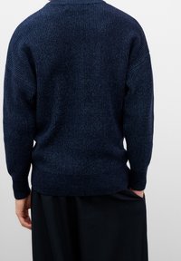 Suéter de punto en azul marino oscuro, con textura acanalada, mangas anchas y un corte relajado. El dobladillo tiene un ligero elástico para un acabado ceñido.