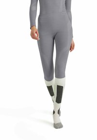Gray athletic leggings with a fitted design, featuring textured accents and a high waistband, paired with white and gray socks with dark patches.