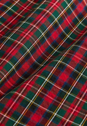 Tissu tartan rouge et vert avec des lignes croisées dans différentes couleurs, créant un motif écossais classique.