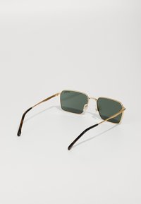 Occhiali da sole con montatura in metallo dorato e lenti verde scuro, con dettagli in acetato tartarugato marrone testurizzato sulle astine. Forma quadrata con design leggero.