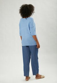 Top bluastro dalla vestibilità ampia con maniche a tre quarti, abbinato a pantaloni dritti blu chiaro. Tessuto morbido, design informale.