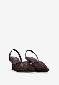 Tacones slingback de malla marrón con punta afilada y tacones medios en bloque. El patrón texturizado se asoma a través del material de malla. Diseño elegante.