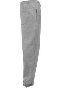 Graue Jogginghose aus weichem Material, mit einem elastischen Bund, seitlichen Taschen und Reißverschlüssen an den Knöcheln für eine verstellbare Passform.