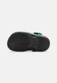 Black rubber outsole with tread pattern, featuring a green and gray strap. The sole is molded with a textured design for traction.