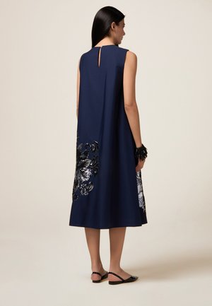 Navy ärmelloses Kleid mit Schlitzrücken, verziert mit silbernen und schwarzen Pailletten in Blumenform am Saum, glatte Stoffstruktur.