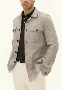 Checkered button-up jacket in beige and brown, made of woven fabric; features two chest pockets and contrasting buttons.
