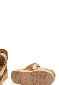 Stivali ankle in suede marrone con dettagli in cucitura crema, suola in gomma robusta, punta arrotondata e suola testurizzata.