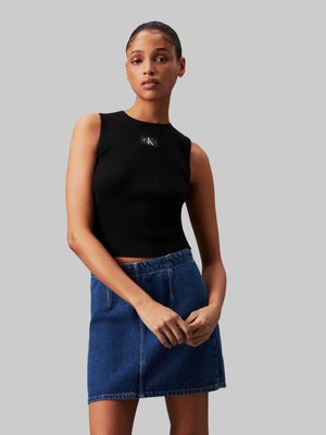 Top corto negro de canalé con el logo de CK, combinado con una falda de denim azul con un corte relajado y cintura elástica.