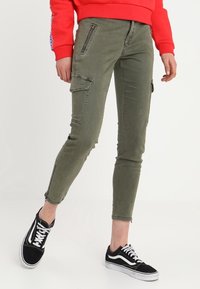 Olivgrön cargobyxor med skinny fit, två sidofickor och dragkedjedetaljer. Har en fransad fåll och är tillverkade i lätt bomullsblandning.