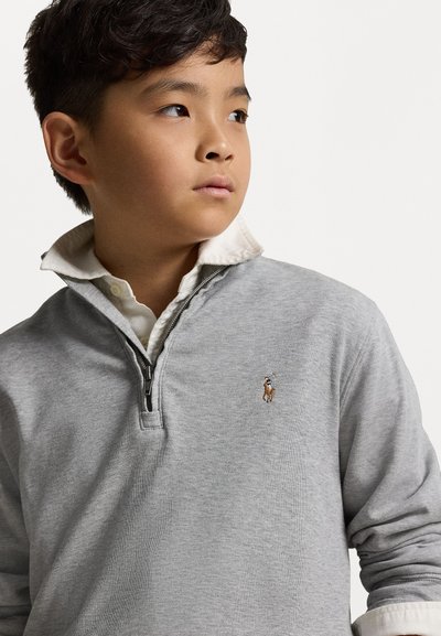 Pullover cinza com um design de meia zip, apresentando uma camisa branca de colarinho por baixo. Inclui um logo bordado no lado esquerdo do peito.