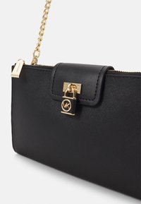 Clutch in pelle nera con finitura texturizzata, accessori in oro e tracolla a catena. Presenta un pattino frontale con un lucchetto decorato con logo.