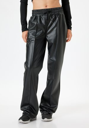 Zwarte neplederen broek met een elastische tailleband, plooien aan de voorkant en taps toelopende enkels, met een gladde, glanzende textuur.
