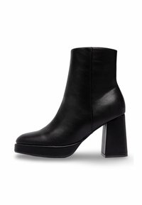 Bottine en cuir noir avec talon bloc et bout arrondi, profil latéral sur fond blanc.