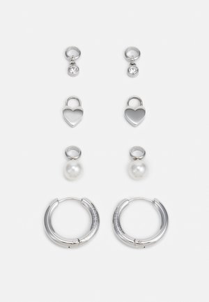 Tre paia di orecchini in argento: piccoli chiodini con pietre trasparenti, ciondoli a forma di cuore e grandi orecchini a cerchio con una finitura texturizzata.