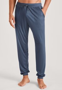 Heren loungebroeken in marineblauw, gemaakt van lichtgewicht, zachte stof. Voorzien van een elastische tailleband met trekkoord en twee zijzakken.