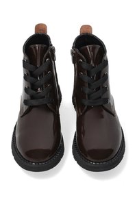 Ciemnobrązowe lakierowane botki za kostkę z okrągłym noskiem, czarnymi sznurowadłami i czarną gumową podeszwą. Posiadają beżową pętelkę na pięcie, co ułatwia zakładanie.