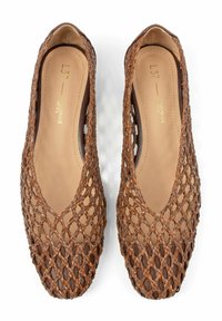 Zapatos planos tejidos de color marrón con un diseño abierto de red y puntera redondeada. Forro interior liso en tono beige y una sutil marca en la plantilla.