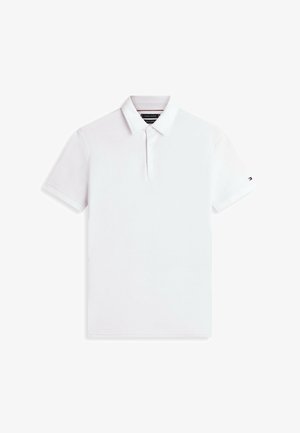 Polo blanco de manga corta con cuello, tres botones y un pequeño logotipo en la manga izquierda, mostrado sobre una superficie plana.