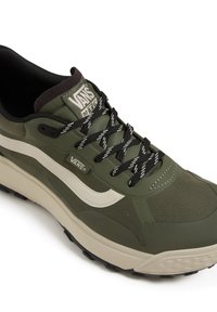 Baskets Vans vertes avec une tige texturée, une bande latérale blanche, des lacets noirs et une semelle épaisse beige avec une semelle à motif.