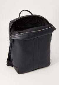Black leather backpack with a structured design, featuring a zippered top, single handle, and interior pocket, all in a matte finish.