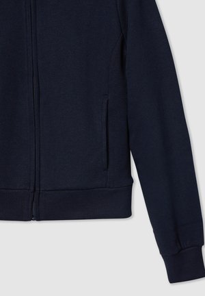 Giacca zip blu navy con polsini e orlo a coste, tasca laterale e texture liscia. Realizzata in tessuto morbido e resistente.