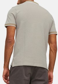 Kortærmet grå polo-shirt med kontrasterende hvid og beige kant på kraven og ærmerne. Blødt bomulds materiale, afslappet pasform.